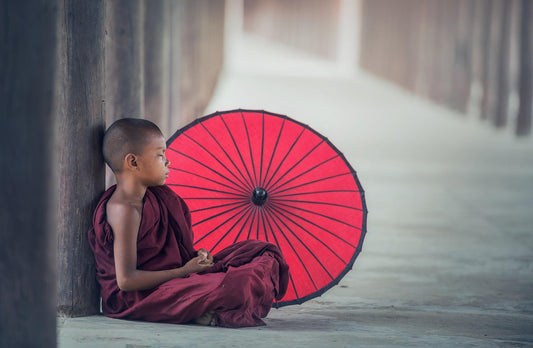 Junger buddhistischer Mönch mit Schirm